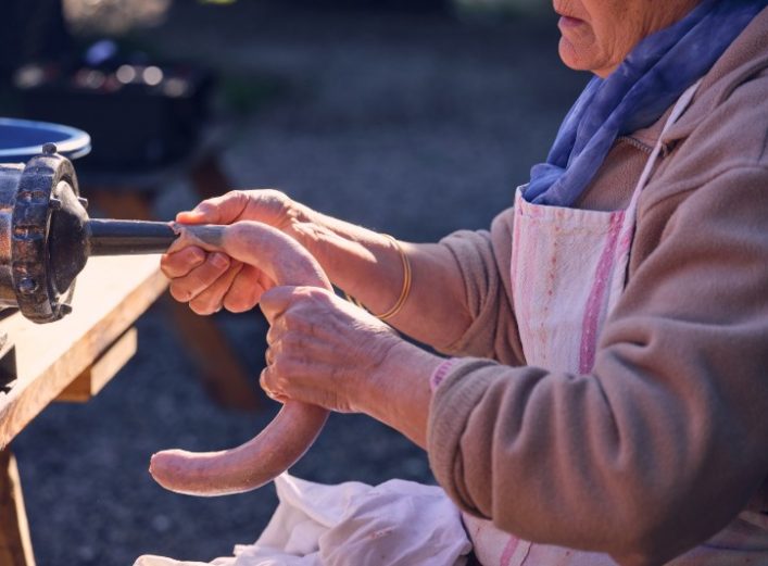 Señora en plena acción de cómo se hacen los chorizos, con una máquina y tripa. Suministros La Ronda.