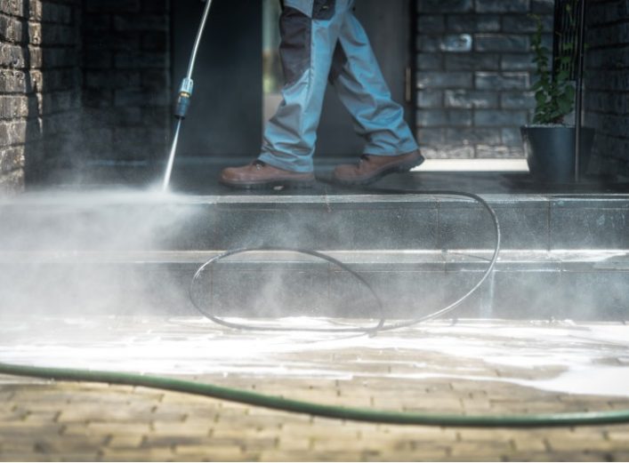 Un hombre limpia el exterior de la casa con una hidrolimpia/dora . | Suministros La Ronda
