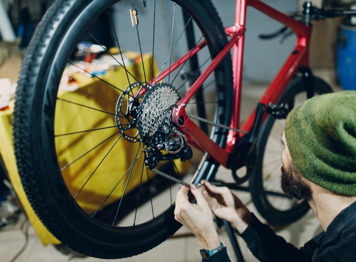 Mecánico de bicicletas repara la cadena de una bici de montaña, objeto en dónde no usar WD-40. | SUMINISTROS LA RONDA