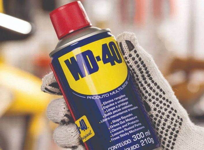 WD-40 usos menos conocidos. Mano con guantes de trabajo que sujeta un bote de lubricante WD-40